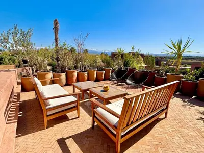 a patio with chairs and tables and potted plants at Palais Kenza in Marrakech