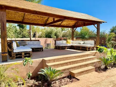 a wooden pergola with couches and a patio at Palais Kenza in Marrakech