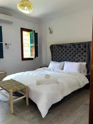 a bedroom with a large white bed with a black headboard at Riad suite for families and groups in Marrakech