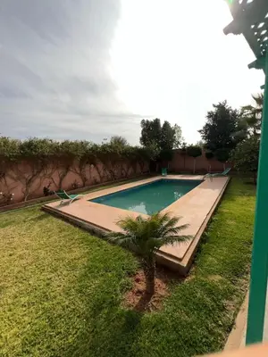 a swimming pool with a palm tree in a yard at Riad suite for families and groups in Marrakech