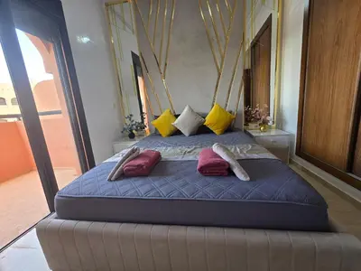 a large bed with pillows on it in a bedroom at Luxury Apartment in Marrakech Premium Village 5 Pools free Parking in Marrakech
