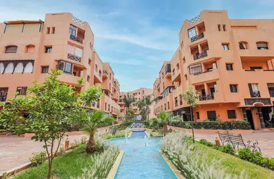 a street with two tall buildings and a river in front at Luxury Apartment in Marrakech Premium Village 5 Pools free Parking in Marrakech