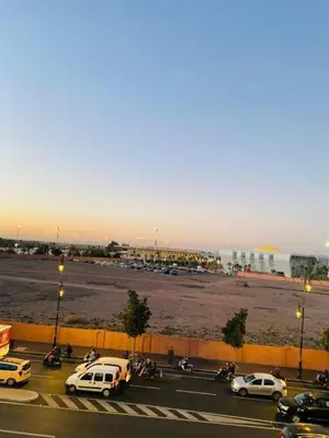 a parking lot with cars parked in a parking lot with a field at Julie Airport Boarding Apartment in Marrakech