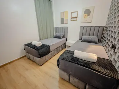 two beds in a room with wooden floors at Cozy Apt Close to Gueliz Medina in Marrakech