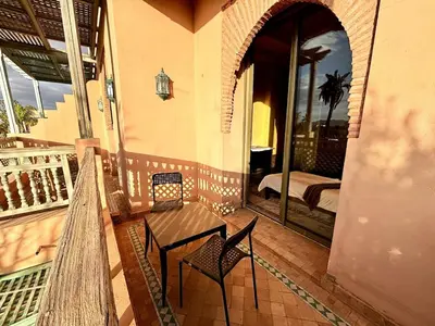 a porch of a house with a bench and a bedroom at 2 bedroom palmeraie, pools & 3 terraces in Marrakech