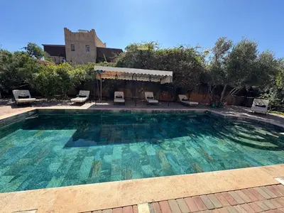 a large swimming pool with chairs in a yard at Splendide Villa avec piscine in Marrakech