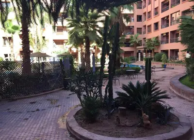 a courtyard with palm trees and tables and a building at Palace-Apartment-Marrakech in Marrakech