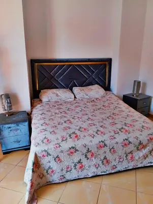 a bedroom with a bed with a floral bedspread at Appartement calme et spacieux pour famille in Marrakech
