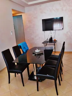 a dining room with a table and black chairs at Appartement calme et spacieux pour famille in Marrakech