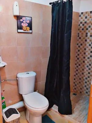 a bathroom with a toilet and a black shower curtain at Appartement calme et spacieux pour famille in Marrakech
