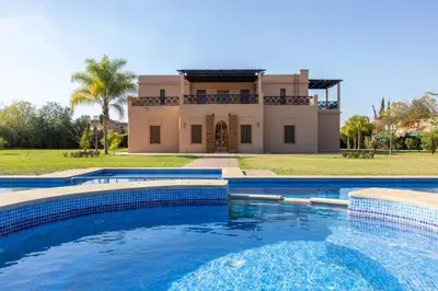 a villa with a swimming pool in front of a house at Villa Dar zitoune in Marrakech