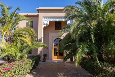 a house with palm trees in front of it at Villa Dar zitoune in Marrakech