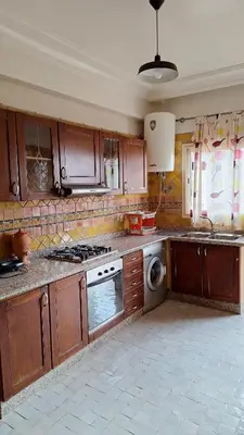 a kitchen with wooden cabinets and a stove top oven at MELBARI Central-Appart in Marrakech