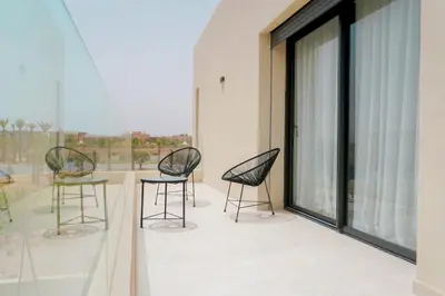 three chairs and a table on a balcony at Villa Emeraude 15 minutes du centre in Marrakech