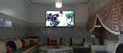 a living room with a couch and a tv on a wall at Appartement à louer in Marrakech