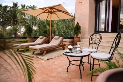 a patio with a table and chairs and an umbrella at Luxury Resort Loudi Marrakech in Marrakech