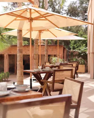 an outdoor patio with tables and chairs with umbrellas at Luxury Resort Loudi Marrakech in Marrakech