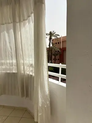 a white curtain on a white balcony with a palm tree at BELDI and contemporary elegance in Marrakech