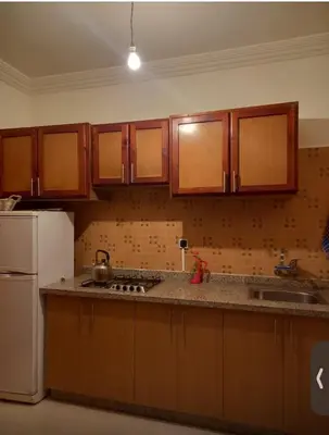 a kitchen with wooden cabinets and a white refrigerator at Modern 2bedroom full furnished in downtown in Marrakech