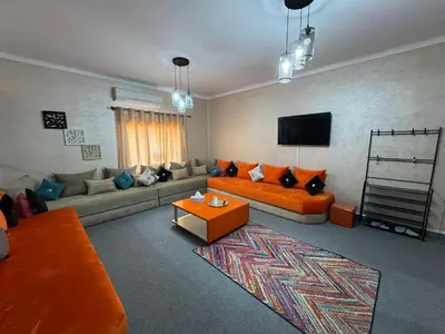 a living room with an orange couch and a tv at Chateau Nougat, Marrakech in Marrakech