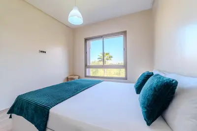a bedroom with a white bed and a window at Elegant Appartement Piscine Golf et Wifi in Marrakech