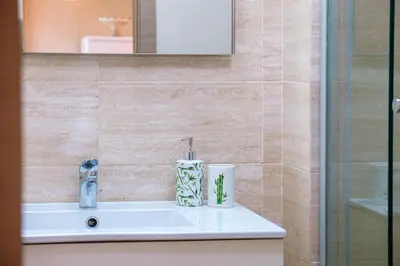 a bathroom with a sink with a shower and a mirror at Elegant Appartement Piscine Golf et Wifi in Marrakech
