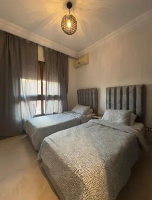a bedroom with two beds and a chandelier at Elegant Apartment Marrakech in Marrakech
