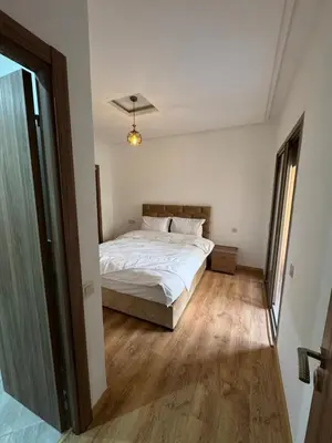 a bedroom with a white bed and a wooden floor at Appartement moderne et chic in Marrakech