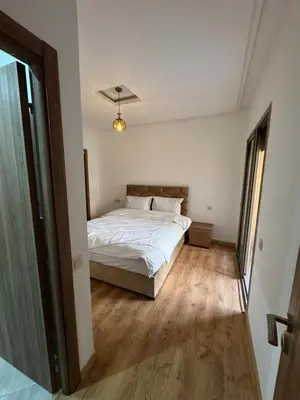a bedroom with a white bed and a wooden floor at Appartement moderne et chic in Marrakech