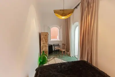 a bedroom with a bed and a table and a window at Riad JONCHÈRES in Marrakech