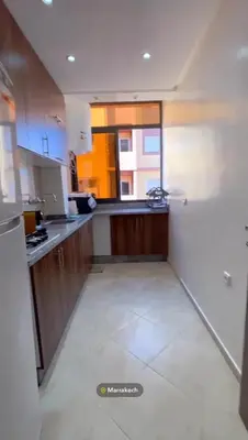 a kitchen with wooden cabinets and a white tile floor at Appartement in Marrakech