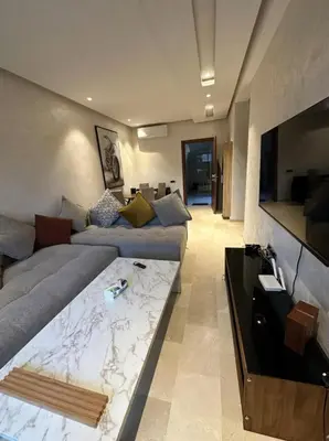 a living room with a couch and a tv at Prestigia Jubaea Marrakech Argane in Marrakech