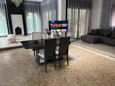 a living room with a table and chairs and a couch at VILLA aVEC PISCINE CHAUFFÉE in Marrakech