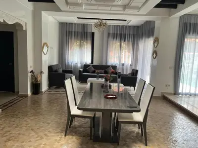 a dining table and chairs in a living room at VILLA aVEC PISCINE CHAUFFÉE in Marrakech