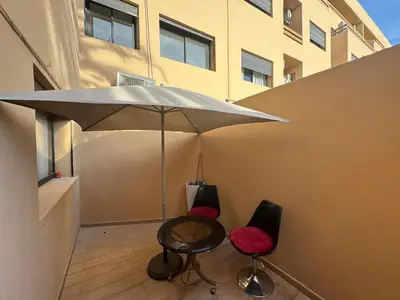 a patio with a table and two chairs and an umbrella at Appartement avec piscine en plein centre de Marrakech in Marrakech