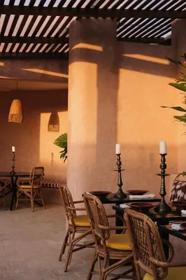 a patio with chairs and tables and a wall at The Mellah Hotel in Marrakech