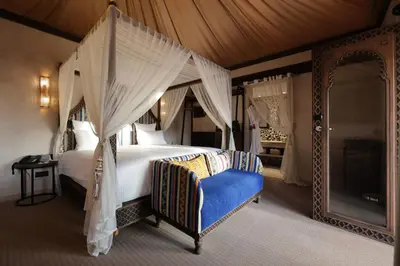 a bedroom with a canopy bed and a blue chair at Palmeraie Oasis Camp - A member of Barcelo Hotel Group in Marrakech