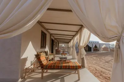 a porch of a house with a chair and a table at Palmeraie Oasis Camp - A member of Barcelo Hotel Group in Marrakech