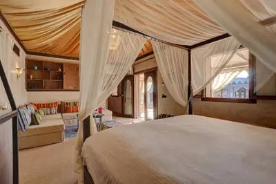 a bedroom with a canopy bed and a living room at Palmeraie Oasis Camp - A member of Barcelo Hotel Group in Marrakech