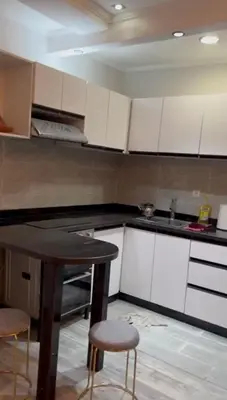 a kitchen with white cabinets and a table and stools at 2-bedroom flat in Gueliz in Marrakech