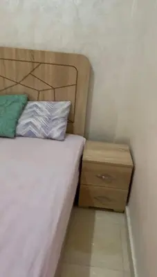 a bed with a wooden headboard next to a night stand at 2-bedroom flat in Gueliz in Marrakech