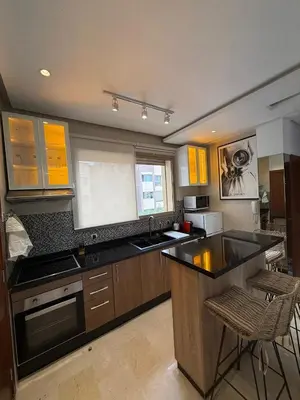 a kitchen with yellow cabinets and a black counter top at Appartement cosy pour 4 personnes in Marrakech