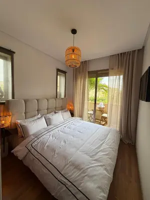 a bedroom with a large white bed and a chandelier at Appartement cosy pour 4 personnes in Marrakech