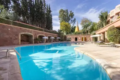 a large blue swimming pool next to a building at Luxury Apartment with Pool Large Terrace & Balconies in Hivernage Marrakech in Marrakech