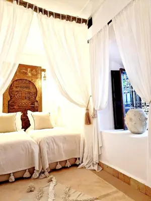 two beds in a bedroom with white curtains at Riad Dar El Mahja in Marrakech