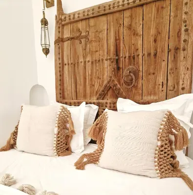 a bed with white pillows and a wooden headboard at Riad Dar El Mahja in Marrakech