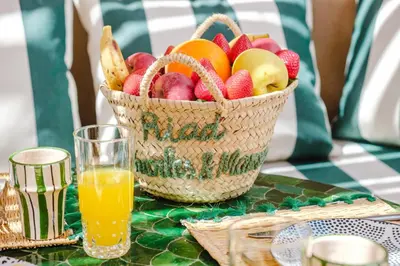 a basket of fruit on a table with a glass of orange juice at Riad Chama 10mn from Jamaa Al Fna in Marrakech