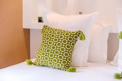 a green pillow sitting on a bed with white pillows at Riad Chama 10mn from Jamaa Al Fna in Marrakech