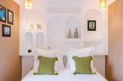 a bedroom with a white bed with pillows and shelves at Riad Chama 10mn from Jamaa Al Fna in Marrakech