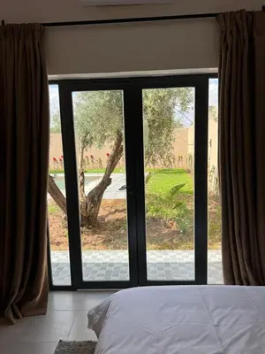 a bedroom with a large window with a view of a yard at Villa JADE with private pool only family in Marrakech
